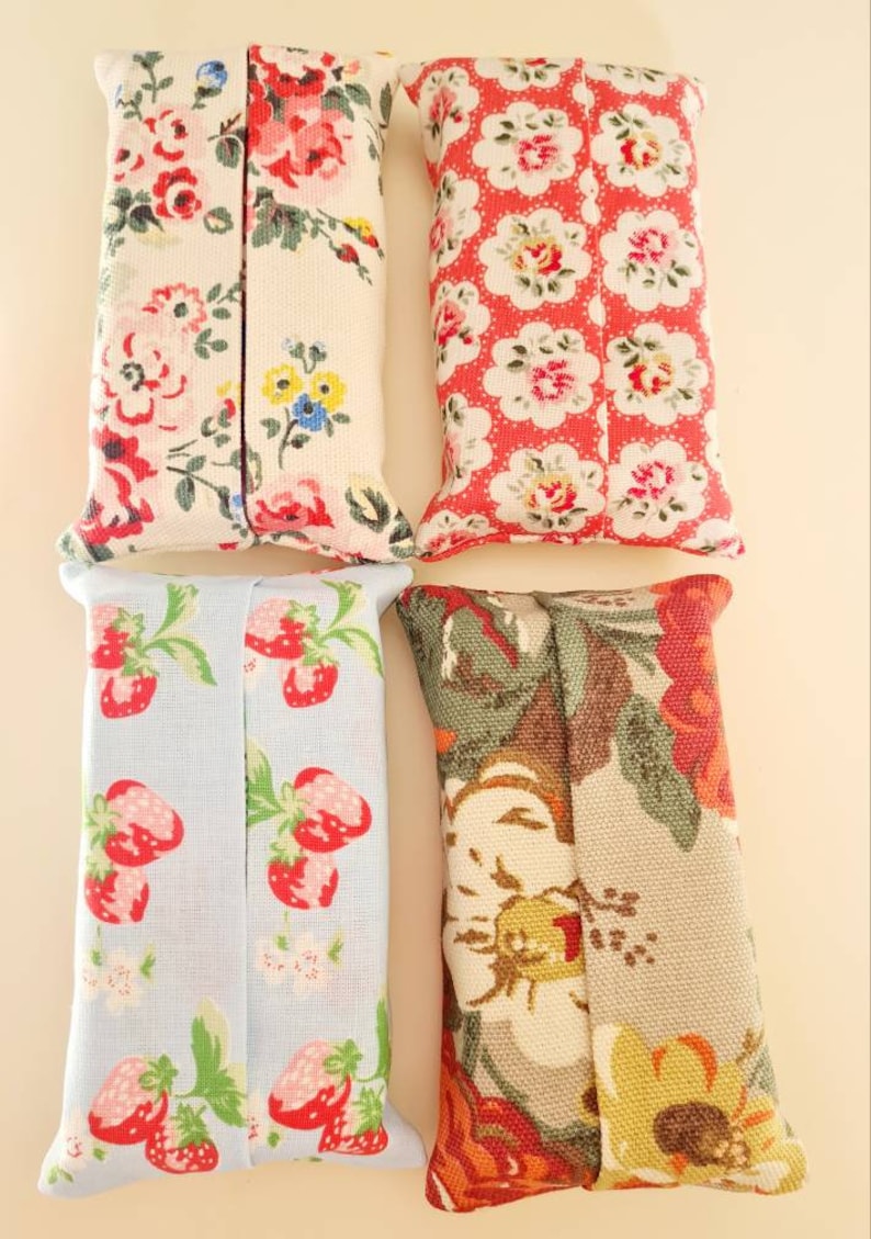 Pode incluir: Quatro capas de tecido para caixa de len&ccedil;os de papel. Uma &eacute; branca com estampa floral rosa e vermelha, outra &eacute; vermelha com estampa floral branca, uma &eacute; azul claro com estampa de morangos vermelhos e outra &eacute; bege com estampa floral vermelha, verde e amarela.