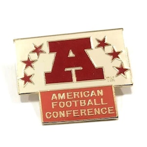 May include: A rectangular pin with a cream-colored background and a red "A" in the center, surrounded by red stars. Below the "A" is a red rectangle with the words "AMERICAN FOOTBALL CONFERENCE" in gold lettering.