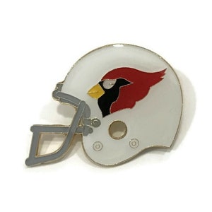 May include: A white football helmet with a red cardinal bird logo. The helmet is made of metal and has a gold trim.