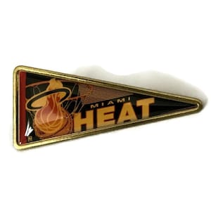 May include: A gold-colored pin shaped like a pennant with the Miami Heat logo. The logo features a basketball with a flame inside and the words "Miami Heat" in orange.