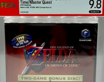 Może przedstawiać: Zapieczętowany i oceniony przez PSA 9.8 egzemplarz gry The Legend of Zelda: Ocarina of Time/Master Quest na konsolę Nintendo GameCube. Okładka gry ma ciemnoczerwone tło z dwoma logotypami Zelda, naklejką 1998 Game of the Year oraz oceną ESRB E.
