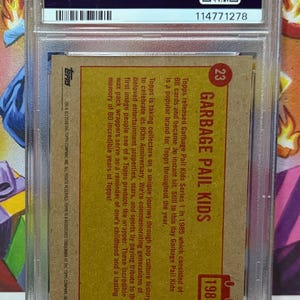 K&ouml;nnte beinhalten: Eine bewertete Garbage Pail Kids Sammelkarte von 1985 mit dem Serientitel und der Nummer 23. Die Karte befindet sich in einer Schutzh&uuml;lle mit einem PSA-Authentifizierungsetikett.