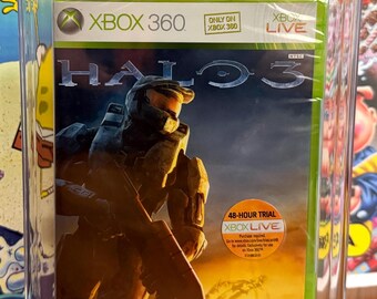 Puede incluir: Un videojuego Halo 3 para Xbox 360 sellado de fábrica, encapsulado en una funda protectora PSA transparente con una calificación de 9.0. La portada muestra a Master Chief con un rifle ante un atardecer y una pegatina de prueba de Xbox Live.