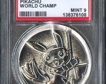 Puede incluir: Una moneda de plata con Pikachu en un estuche protector. La moneda está etiquetada como "2024 P.M. COIN PROMO PIKACHU WORLD CHAMP" con una calificación "MINT 9". La moneda tiene un diseño detallado de Pikachu.