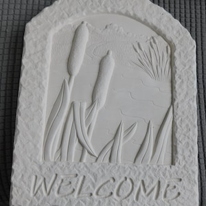 May include: A rustic wooden sign with the text "Welcome to our home" in white lettering. The sign features a distressed finish and a simple, inviting design, perfect for front door decor.