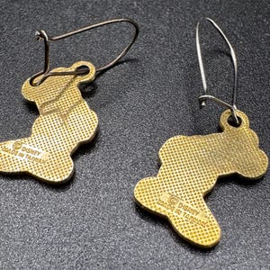 K&ouml;nnte beinhalten: Ein Paar goldfarbene Ohrh&auml;nger. Jeder Ohrring hat eine stilisierte Form mit strukturierter Oberfl&auml;che und einem Drahtb&uuml;gel. Die Ohrringe sind mit "Disney Made in Taiwan" gekennzeichnet.