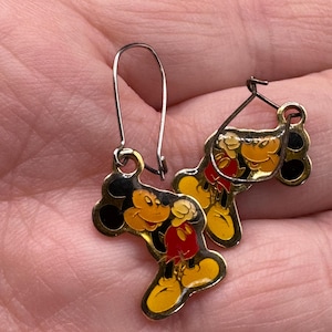 K&ouml;nnte beinhalten: Ein Paar Vintage-Mickey-Mouse-Ohrringe. Die Ohrringe haben eine goldfarbene Metallkontur mit Emaille-Details in Schwarz, Gelb und Rot. Sie haben einen Hakenverschluss.
