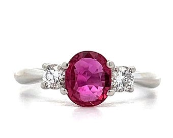 May include: A silver ring featuring a pink oval gemstone flanked by two smaller round white gemstones.