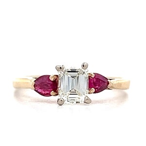 May include: A gold engagement ring with a center emerald cut diamond and two pear-shaped ruby accent stones.