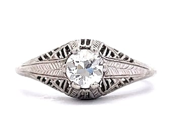 May include: A vintage silver ring with a delicate filigree design and a single round diamond in the center.