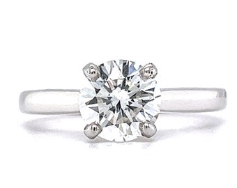 May include: A silver solitaire engagement ring with a round brilliant cut diamond.