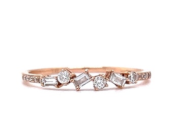 May include: A delicate rose gold band ring with a scattered arrangement of small round and baguette-shaped diamonds.