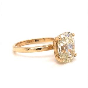 Pode incluir: Um anel de ouro com uma grande gema oval e transparente.