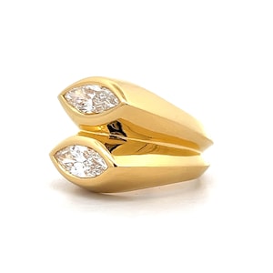 Pu&ograve; includere: Un anello d'oro con due diamanti a forma di marquise incastonati nella fascia.