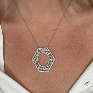 May include: A silver necklace with a hexagonal pendant set with small clear stones. The pendant features a delicate, intricate design with a circular opening in the center.