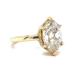 May include: A gold ring with a large, clear, oval-shaped diamond set in a claw setting.