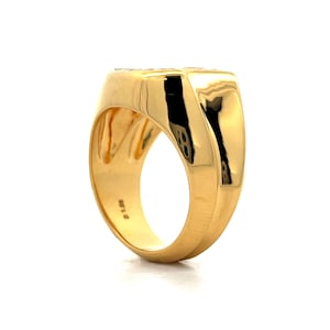 Pu&ograve; includere: Un anello a sigillo in oro con una superficie liscia e arrotondata. L'anello ha una parte superiore piatta e una fascia leggermente curva.
