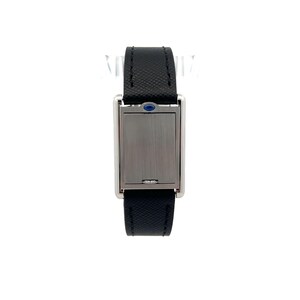 May include: Close-up view of a rectangular wristwatch with a sleek, silver-toned case and a black leather strap. The watch face is concealed behind a silver-toned cover, and a small, dark blue gemstone is visible near the top of the case. The watch has a minimalist design, and the strap appears to be made of textured leather. The overall style suggests a modern and sophisticated timepiece.