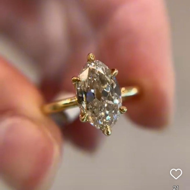 May include: A gold ring with a large, clear marquise-shaped diamond.