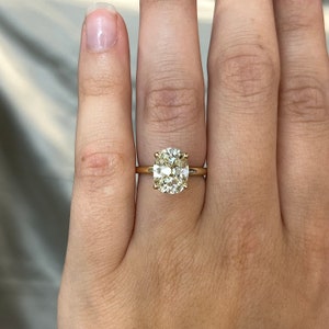 Pode incluir: Um anel de ouro com um grande diamante amarelo claro de forma oval.