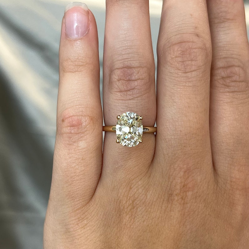 Pode incluir: Um anel de ouro com um grande diamante amarelo claro de forma oval.