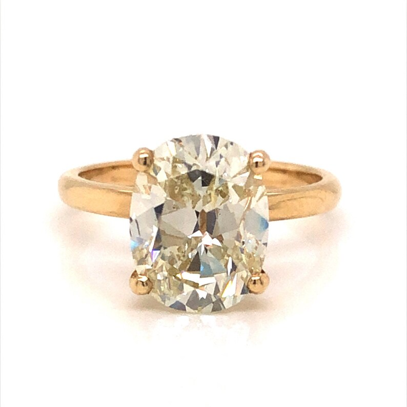 Pode incluir: Um anel de ouro com um grande diamante oval. O diamante &eacute; transparente com um leve tom amarelado.