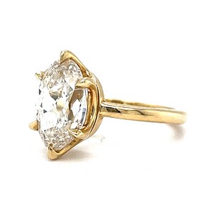 May include: A gold ring with a large, clear, round diamond set in a prong setting.