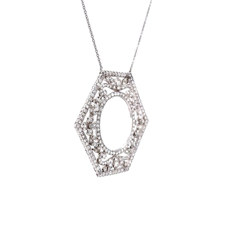 May include: A silver pendant necklace with a hexagonal frame set with clear sparkling stones. The frame has a circular opening in the center.