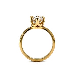May include: A gold solitaire engagement ring with a round brilliant cut diamond set in a four-prong setting.