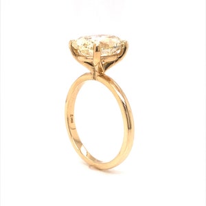 Pode incluir: Um anel de ouro com uma grande gema oval de cor amarelo claro. O anel tem uma banda simples e &eacute; marcado com 5/16 no interior.