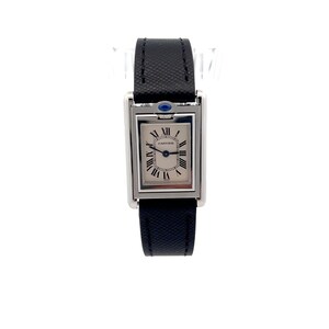 May include: A Cartier Tank watch with a rectangular silver case and a black leather strap. The watch face is white with Roman numerals and a blue cabochon on the crown. The brand name 'CARTIER' is visible on the watch face.