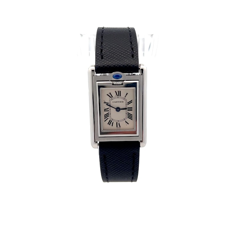 May include: A Cartier Tank watch with a rectangular silver case and a black leather strap. The watch face is white with Roman numerals and a blue cabochon on the crown. The brand name 'CARTIER' is visible on the watch face.