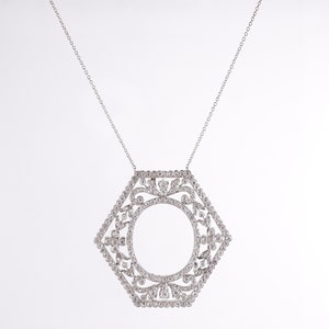 May include: A silver necklace with a hexagonal pendant featuring a delicate, intricate design of small diamonds. The pendant has a circular opening in the center.