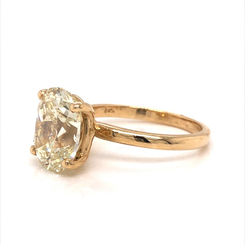 Pode incluir: Um anel de ouro com uma grande gema oval de cor amarelo claro. O anel &eacute; definido em um estilo simples e cl&aacute;ssico.