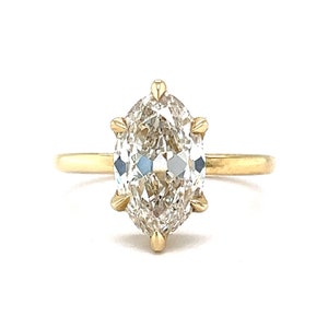 May include: A gold ring with a large, clear, marquise-shaped diamond set in a prong setting.