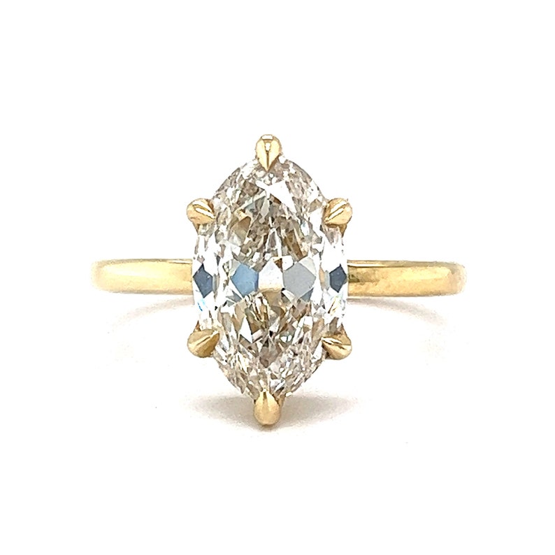 May include: A gold ring with a large, clear, marquise-shaped diamond set in a prong setting.