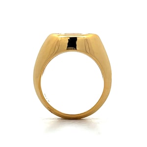 Pu&ograve; includere: Un anello d'oro con una grande pietra preziosa trasparente incastonata al centro. L'anello ha una fascia larga e una finitura liscia e lucida.