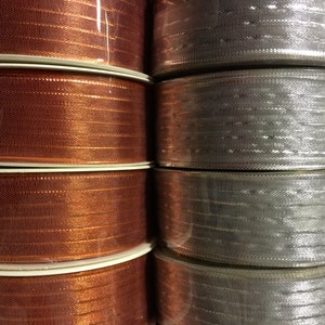 K&ouml;nnte beinhalten: Rollen mit Metallic-Band in Kupfer- und Silberfarben. Das Band ist gl&auml;nzend und hat eine dezente Textur.