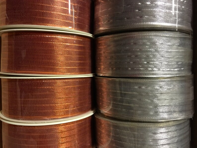 K&ouml;nnte beinhalten: Rollen mit Metallic-Band in Kupfer- und Silberfarben. Das Band ist gl&auml;nzend und hat eine dezente Textur.