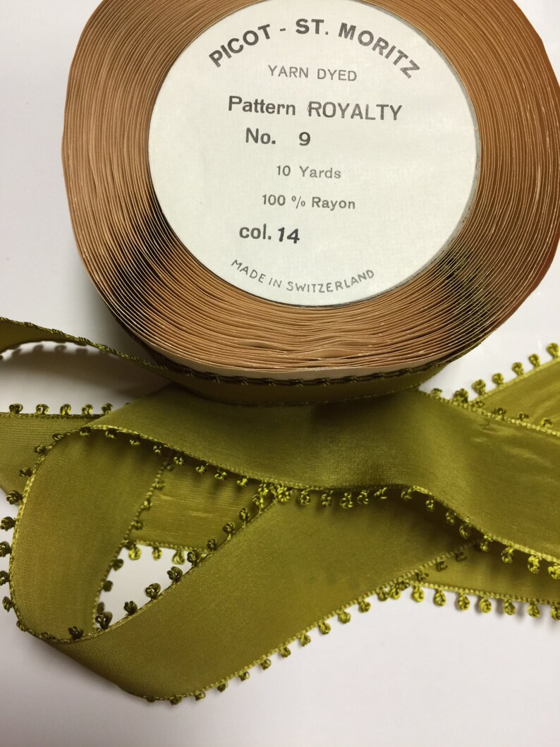 May include: A spool of green rayon ribbon with a picot edge. The label reads "Picot - St. Moritz Yarn Dyed Pattern Royalty No. 9 10 Yards 100% Rayon col. 14 Made in Switzerland".