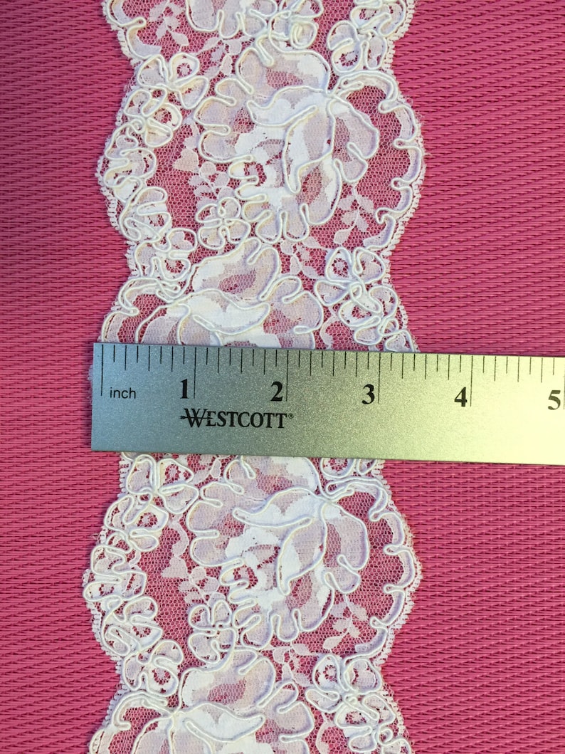 Op de afbeelding: Witte kant met een bloemenpatroon. De kant is ongeveer 5 cm breed.