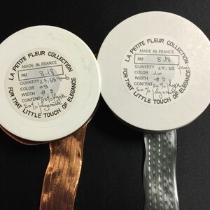 K&ouml;nnte beinhalten: Zwei wei&szlig;e Garnrollen mit Etiketten, auf denen "La Petite Fleur Collection" steht und Details wie "Made in France", "Pat 818", "Menge 2 7/35 Yards", "Farbe #9", "Breite #9" und "Inhalt 50% Seide 50% Nylon" angegeben sind.