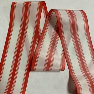 May include: Red and white striped ribbon. The ribbon is made of a silky material and has a subtle sheen.