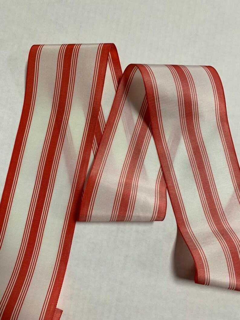 May include: Red and white striped ribbon. The ribbon is made of a silky material and has a subtle sheen.