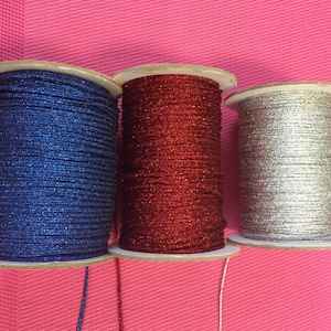 May include: Three spools of sparkly thread, one blue, one red, and one silver.