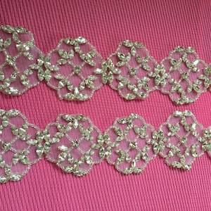 May include: Two rows of gold-coloured, beaded trim with a floral design. The trim is made of small, clear rhinestones and beads.