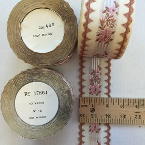 Puede incluir: Dos carretes de cinta floral marrón y blanca con borde festoneado. Los carretes están etiquetados con el texto "Col. 408 100% RAYON" y "Pon 17864 10 YARDS N° 12 MADE IN FRANCE".