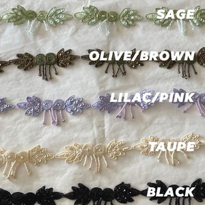 Puede incluir: Primer plano de ocho colores diferentes de ribete de cuentas con un diseño de hoja. Los colores son azul periwinkle, rosa claro, salvia, oliva/marrón, lila/rosa, topo, negro y blanco.