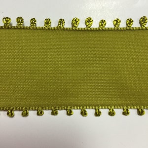 May include: A green ribbon with a decorative edge of small green loops. The ribbon is smooth and has a subtle sheen.