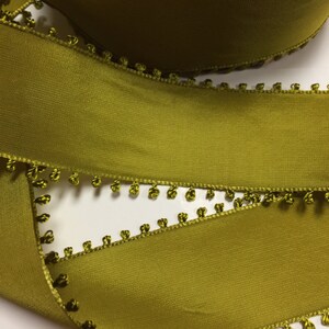 May include: Olive green satin ribbon with a scalloped edge and small pom-poms along the edge.